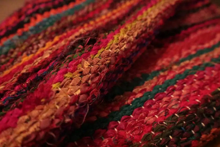 A woven fabric with rich textures in shades of red, orange, and green stripes