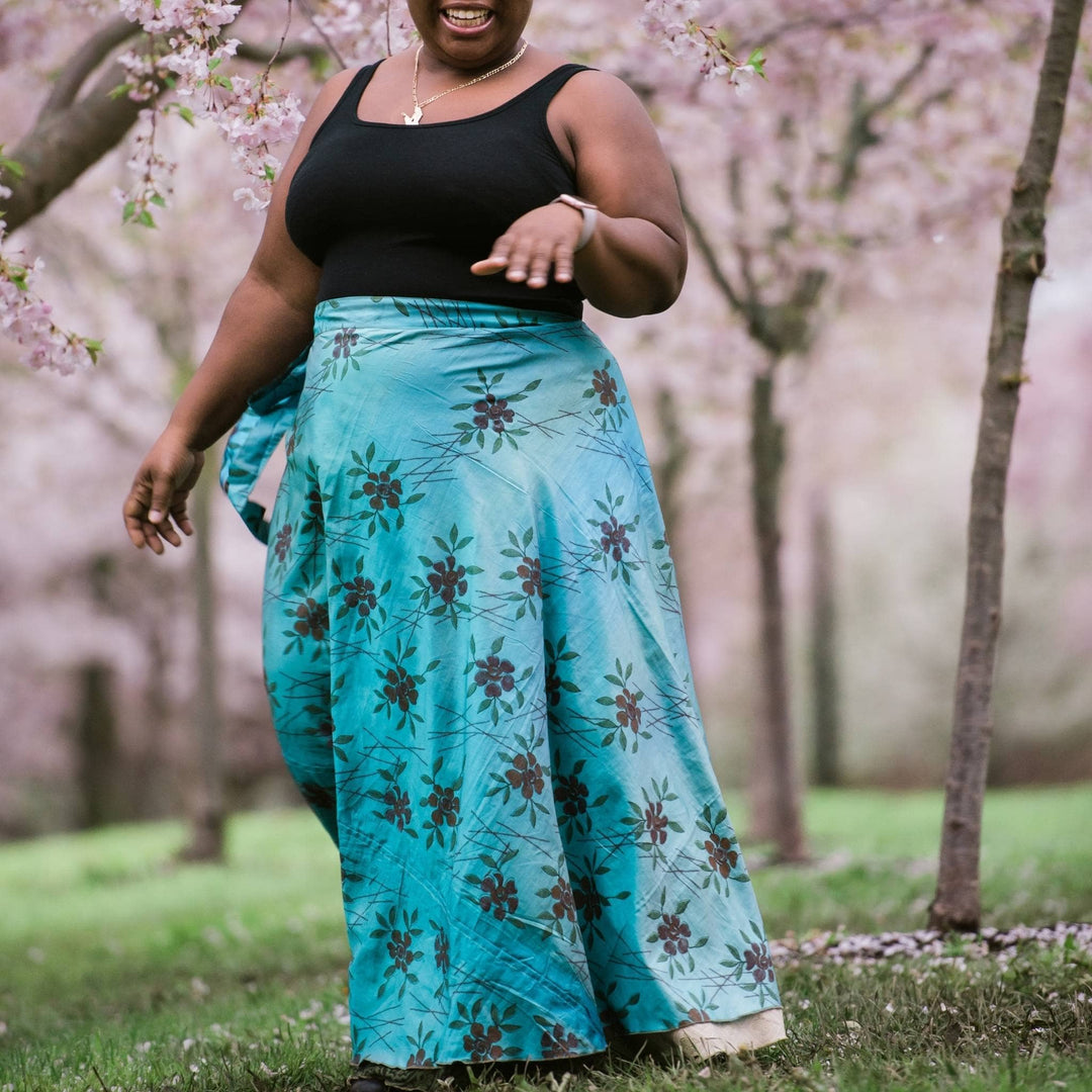 Model standing in front of a cherry blossom tree wearing a one of a kind turquoise ankle length sari wrap skirt in goddess size.  