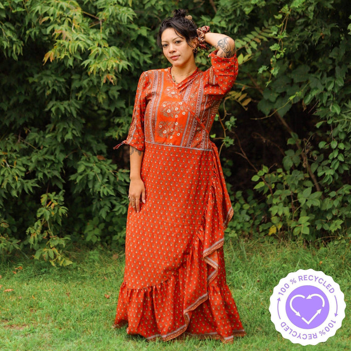 A woman with tattoos in a long warm tone Zaria Wrap Dress in a park.