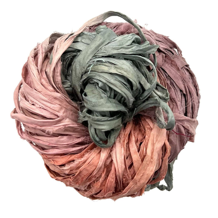 A tightly wound ball of pink, green, and red fabric strips.