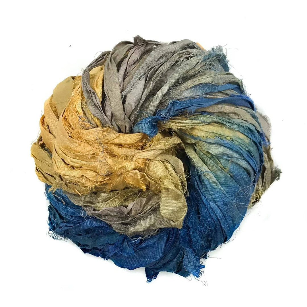 Bundle of ragged multicolored fabric strips in yellow, gray, and blue coiled into a circular shape.