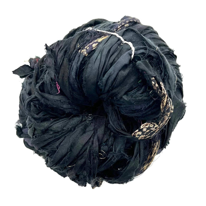 Tightly wound ball of black fabric strips with small gold thread details on a white background.