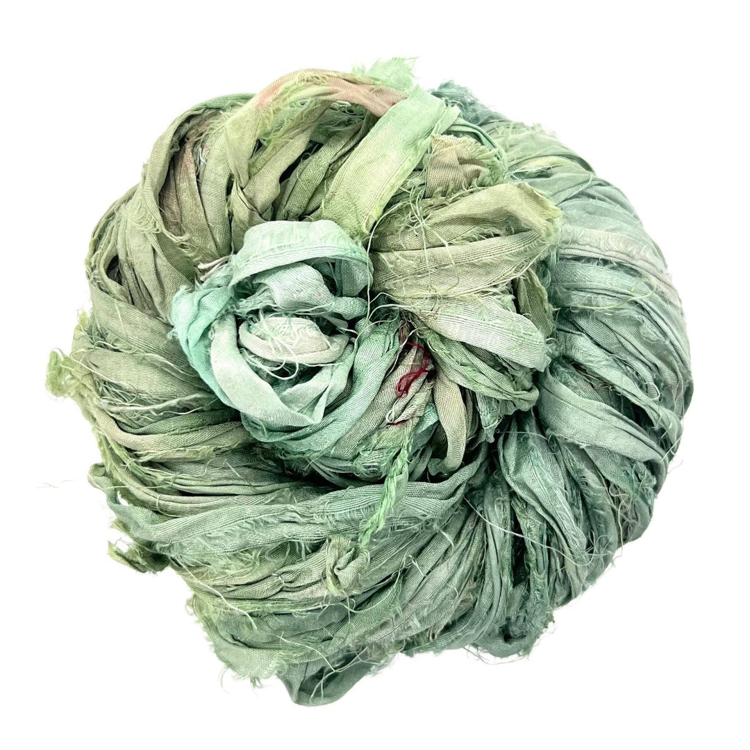 A ball of tangled green fabric strips with frayed edges in varied shades.