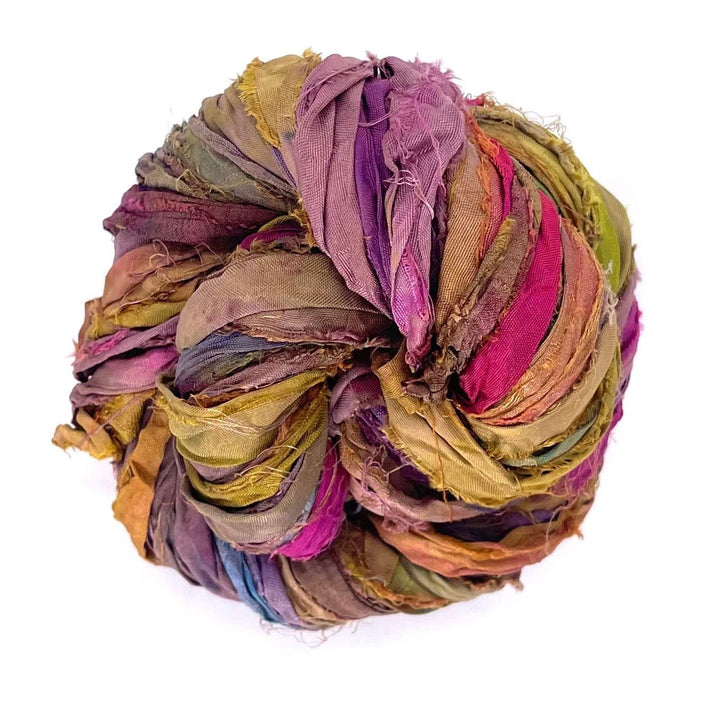 A ball of colorful twisted fabric strips in shades of purple, green, and red.