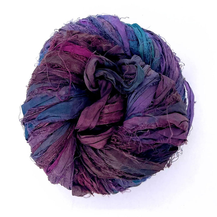 Multicolored yarn ball in shades of purple, blue, and green, twisted into a circular shape.