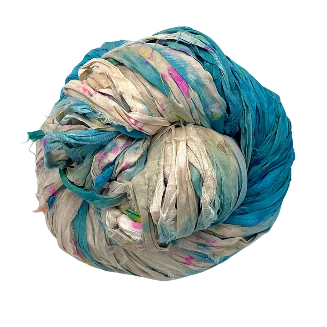 A tightly wound ball of multicolored fabric strips, mainly blue and white with pink and green.