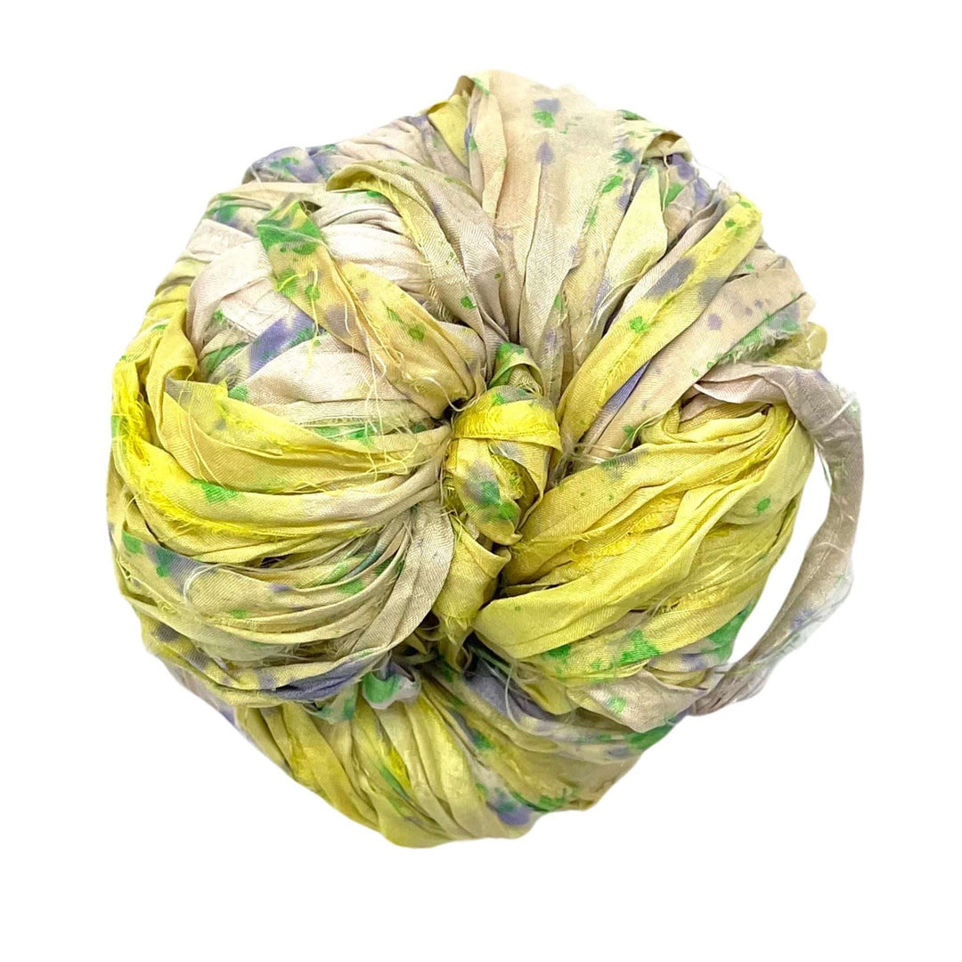 Tightly wrapped ball of multicolored fabric with yellow and green hues against a white background.
