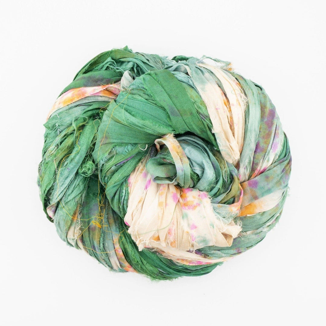 Large ball of colorful fabric featuring green, cream, pink, and orange on a white background.