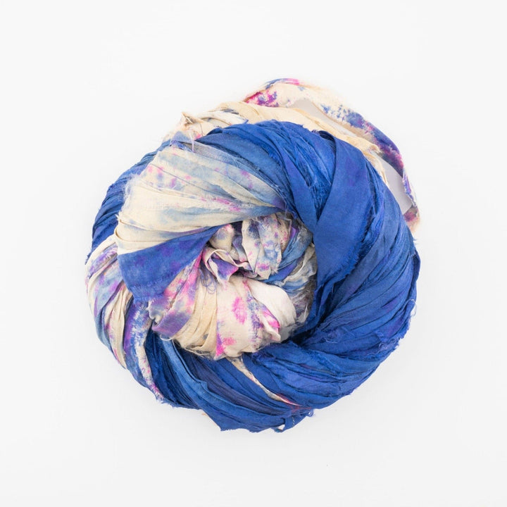 A tightly rolled bundle of blue and beige fabric with pink patterns in a circular shape.